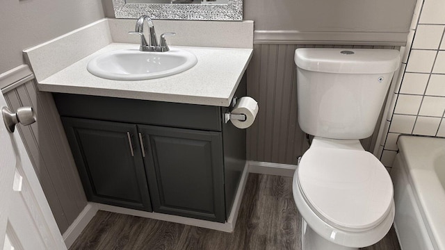 bathroom with wood-type flooring, a washtub, toilet, and vanity