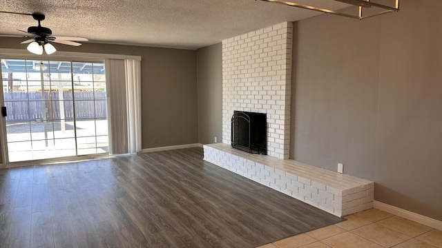 unfurnished living room featuring ceiling fan, a textured ceiling, and a brick fireplace