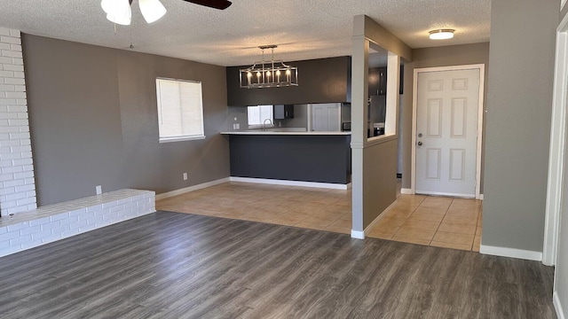 kitchen featuring kitchen peninsula, fridge, ceiling fan, light wood-type flooring, and a textured ceiling