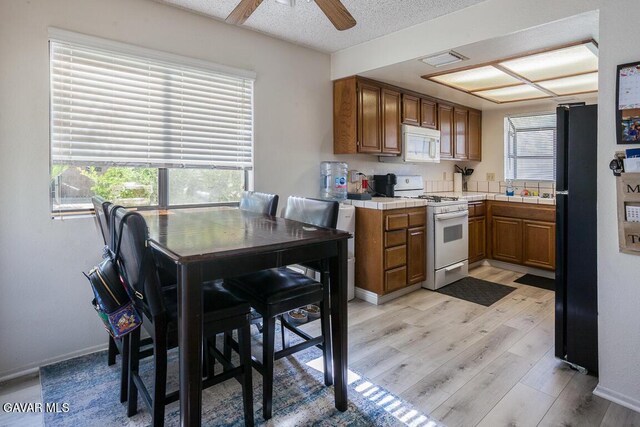 425 W W Ave J5, Unit 37, Lancaster, CA 93534 - kitchen with white appliances, tile counters, brown cabinetry, light wood-style floors, and a ceiling fan
