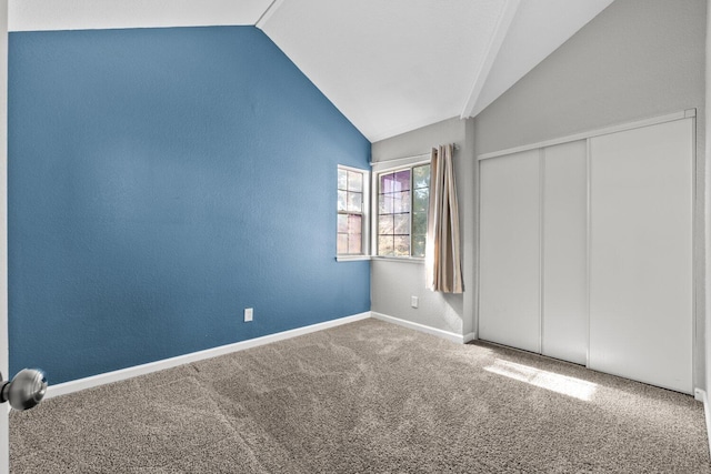 unfurnished bedroom with vaulted ceiling, a closet, and carpet flooring