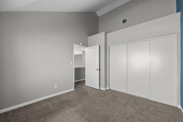 unfurnished bedroom featuring high vaulted ceiling, dark carpet, and a closet