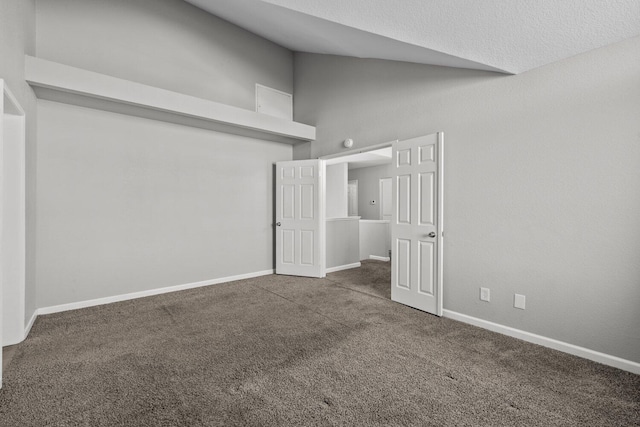 spare room with high vaulted ceiling and dark carpet