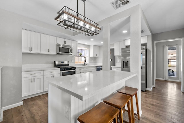 kitchen featuring pendant lighting, stainless steel appliances, and white cabinets