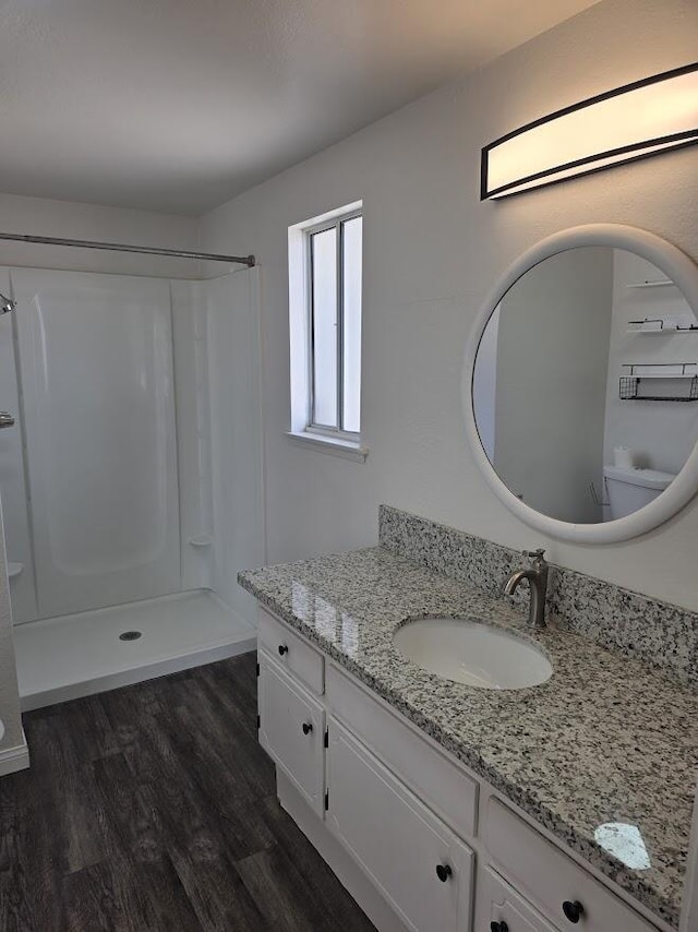 bathroom featuring walk in shower, wood finished floors, and vanity