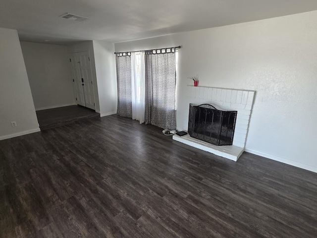 unfurnished living room with dark wood-type flooring, visible vents, a fireplace, and baseboards