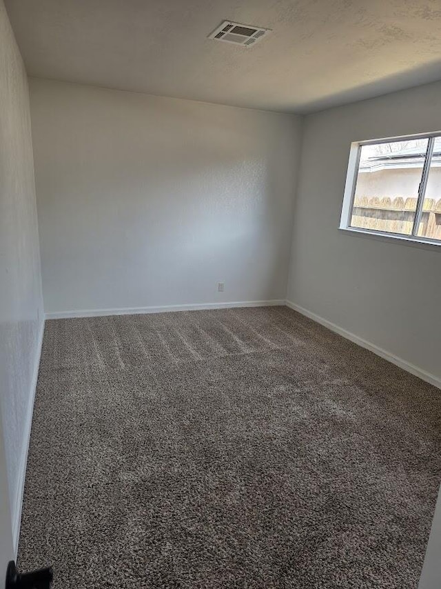 unfurnished room featuring carpet, visible vents, and baseboards