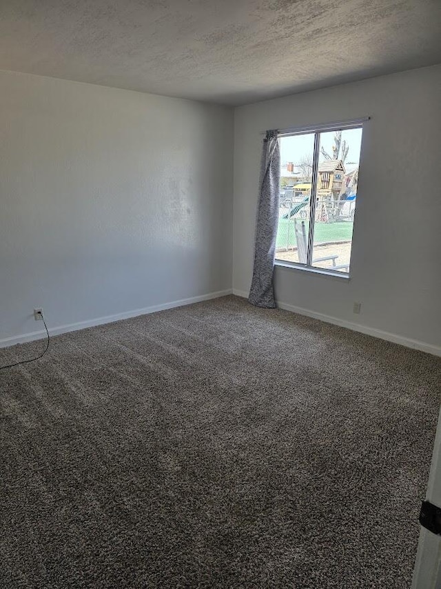empty room with carpet, baseboards, and a textured ceiling