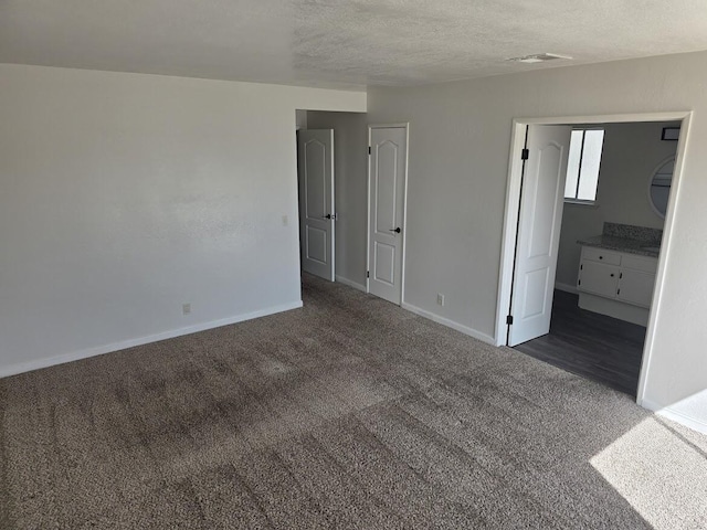unfurnished bedroom featuring a textured ceiling, baseboards, and carpet flooring
