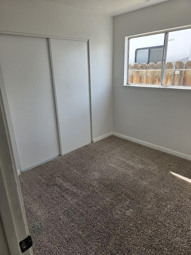 unfurnished bedroom with carpet floors, baseboards, and a closet
