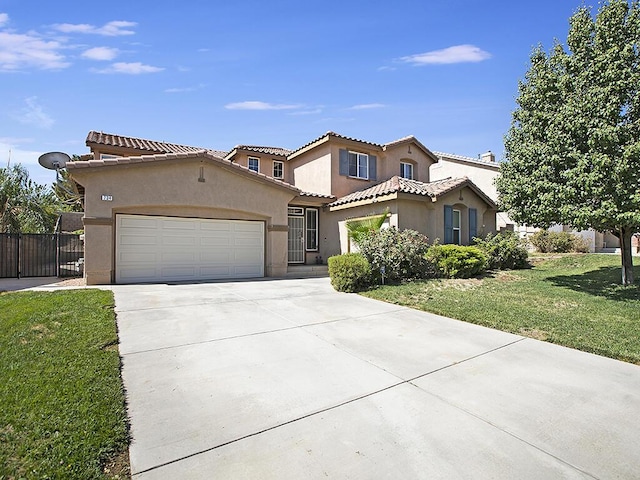 mediterranean / spanish home with an attached garage, concrete driveway, a front yard, a tile roof, and stucco siding