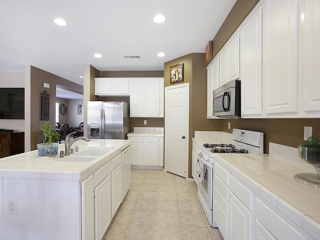 kitchen with tile counters, a sink, recessed lighting, and appliances with stainless steel finishes