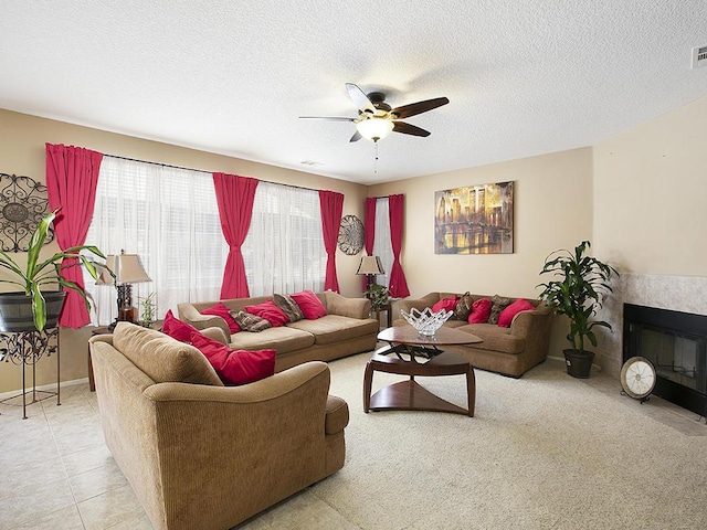 living room with light tile patterned floors, a textured ceiling, visible vents, and a ceiling fan