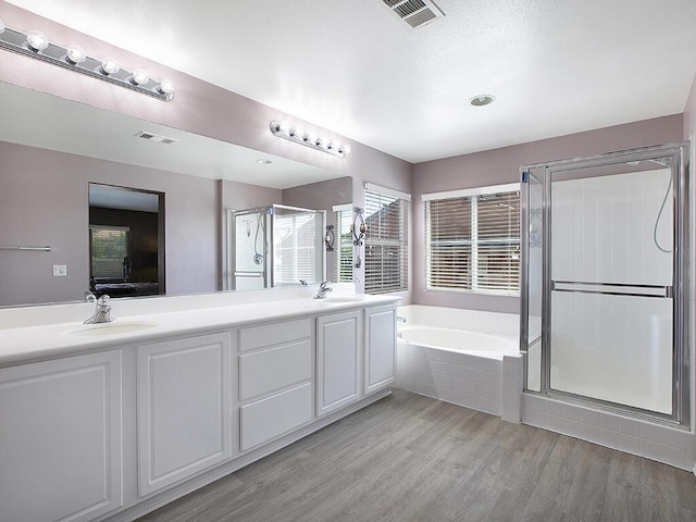 ensuite bathroom with a sink, visible vents, a garden tub, and a stall shower