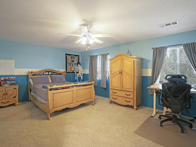 bedroom featuring a textured ceiling, ceiling fan, visible vents, and light colored carpet