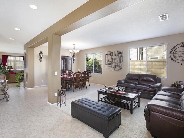 living room with baseboards, a textured ceiling, visible vents, and a notable chandelier