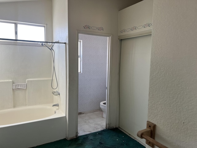 bathroom with toilet, a textured wall, and shower / bathtub combination