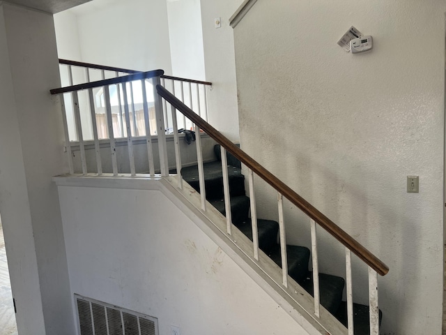 stairway with a textured wall and visible vents