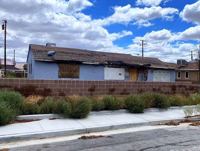 view of front of home featuring fence, stucco siding, and cooling unit