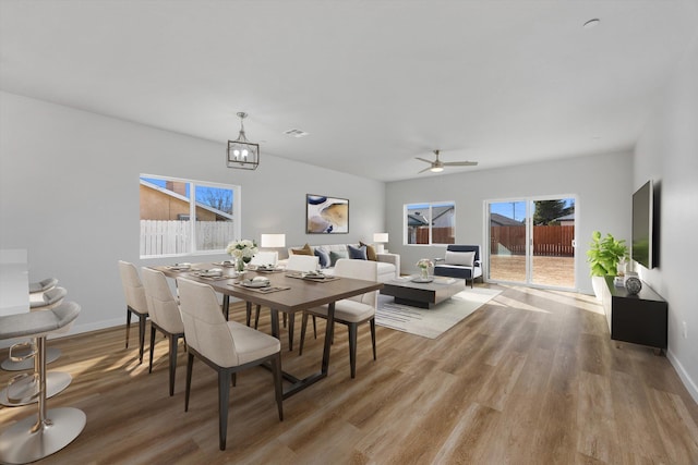 dining area with light wood finished floors, baseboards, and an inviting chandelier