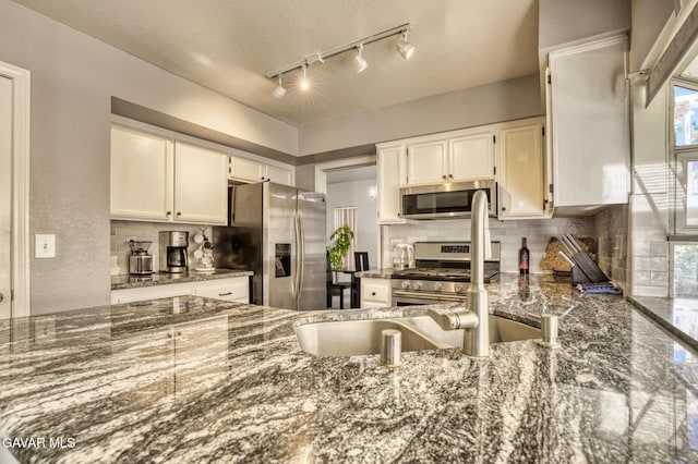 1306 Date Palm Dr, Palmdale, CA 93551 - kitchen featuring appliances with stainless steel finishes, decorative backsplash, dark stone counters, and white cabinets
