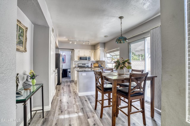 1306 Date Palm Dr, Palmdale, CA 93551 - dining room featuring a textured wall, light wood finished floors, and a textured ceiling