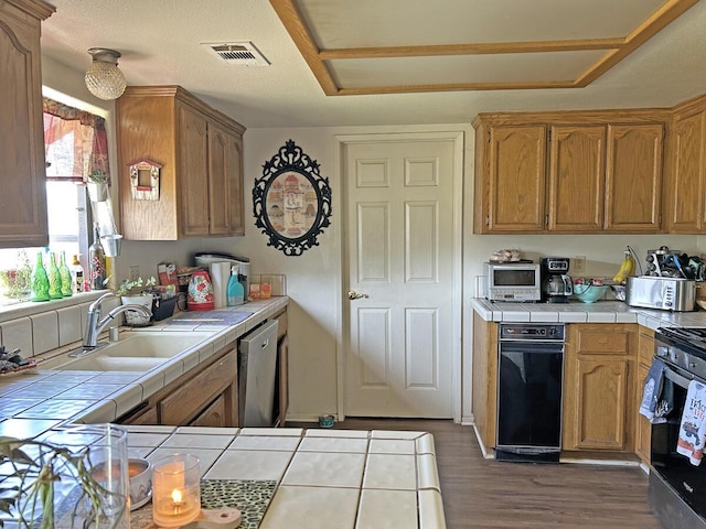 kitchen with a sink, stainless steel appliances, tile countertops, and visible vents