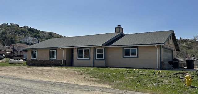 ranch-style home featuring a chimney and a garage