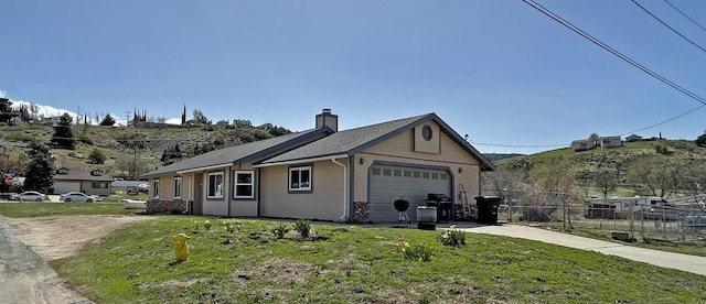 view of front of property with concrete driveway, fence, an attached garage, a front lawn, and a chimney