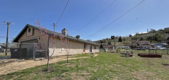 view of home's exterior featuring a chimney, a garage, fence, and a lawn