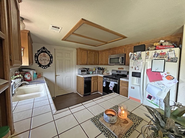 kitchen with visible vents, dark tile patterned floors, stainless steel appliances, tile countertops, and a sink