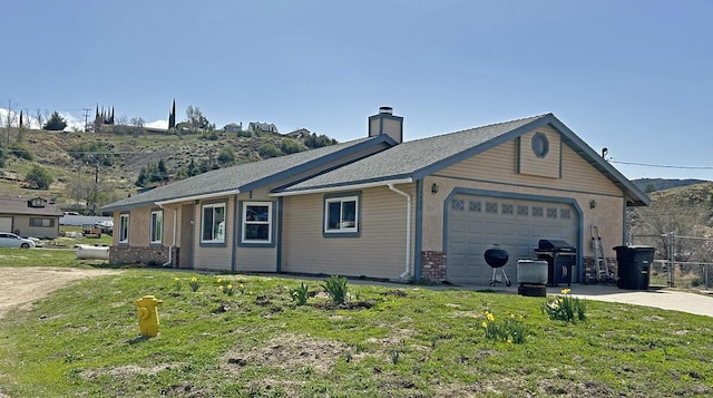 view of side of property with a yard, a chimney, an attached garage, and concrete driveway