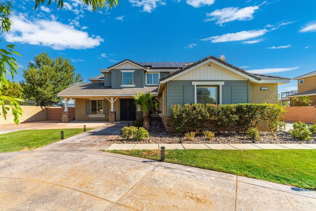 view of front of property featuring a front lawn and solar panels