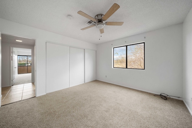 unfurnished bedroom featuring a closet, carpet flooring, a textured ceiling, and ceiling fan