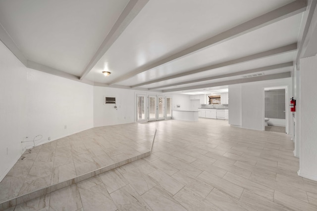 unfurnished living room featuring beamed ceiling and visible vents