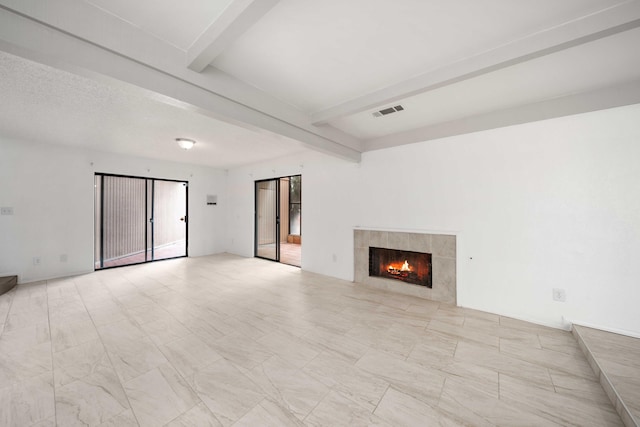 unfurnished living room featuring visible vents, beam ceiling, and a tiled fireplace