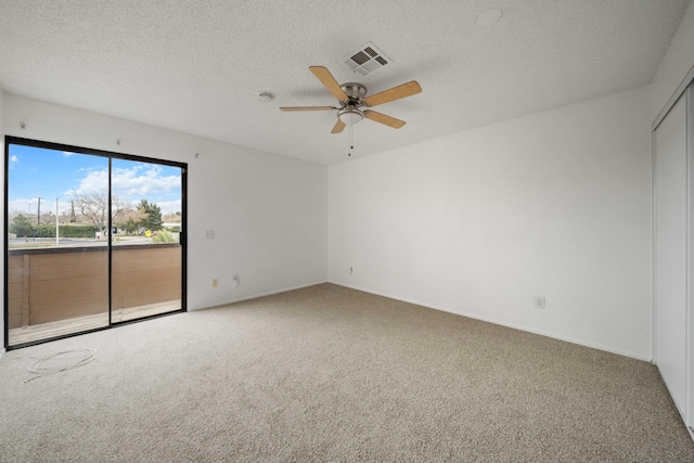 carpeted spare room featuring a textured ceiling, visible vents, and ceiling fan