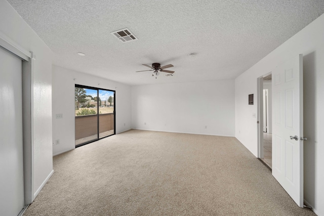 carpeted spare room with visible vents, a textured ceiling, and ceiling fan