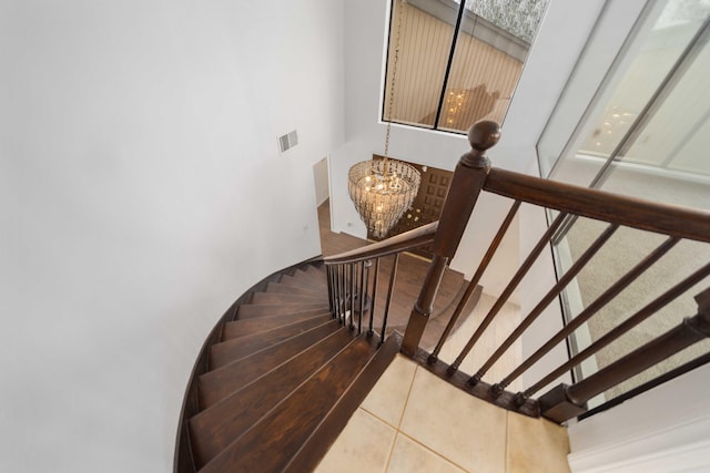 stairs featuring tile patterned flooring, visible vents, and an inviting chandelier