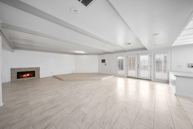 unfurnished living room featuring beamed ceiling, visible vents, and a tile fireplace