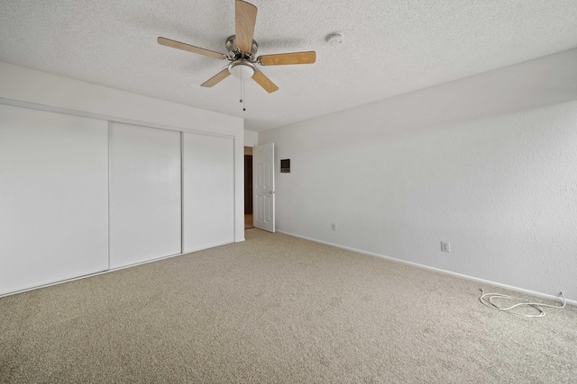 unfurnished bedroom with a ceiling fan, baseboards, a closet, a textured ceiling, and light carpet