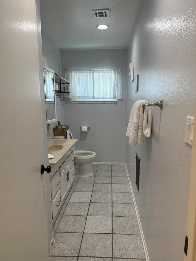 bathroom with toilet, vanity, and tile patterned flooring