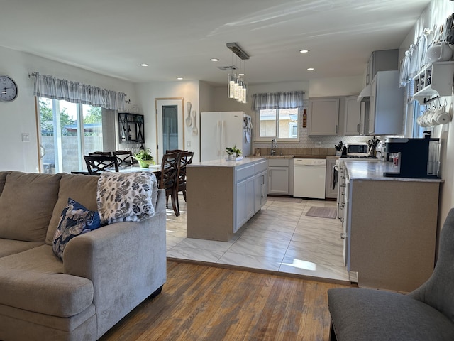 kitchen featuring white appliances, gray cabinets, decorative light fixtures, and a center island