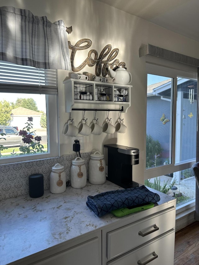 kitchen with white cabinets, wood-type flooring, light stone countertops, and a healthy amount of sunlight