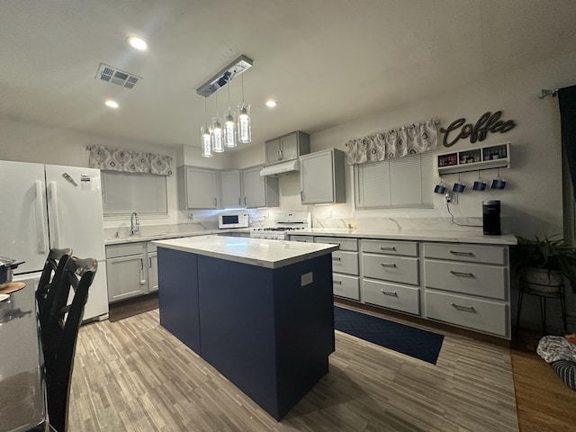 kitchen with white appliances, wood-type flooring, hanging light fixtures, a center island, and backsplash