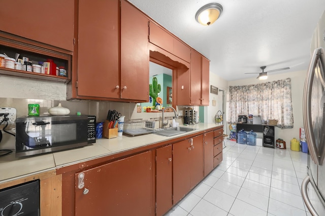 kitchen with light tile patterned flooring, sink, a textured ceiling, stainless steel refrigerator, and ceiling fan