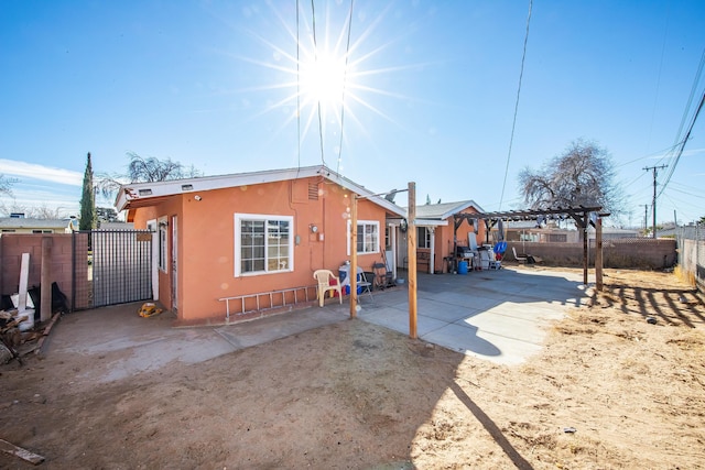 rear view of property featuring a pergola and a patio area