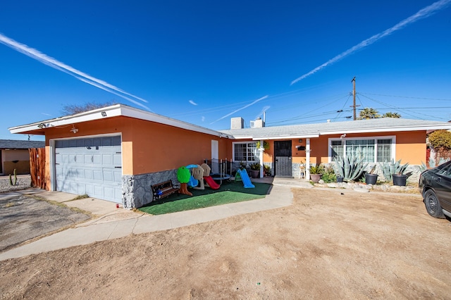 ranch-style home featuring a garage and a playground