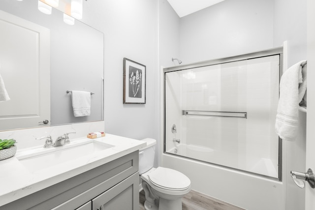 full bathroom featuring toilet, vanity, combined bath / shower with glass door, and wood-type flooring