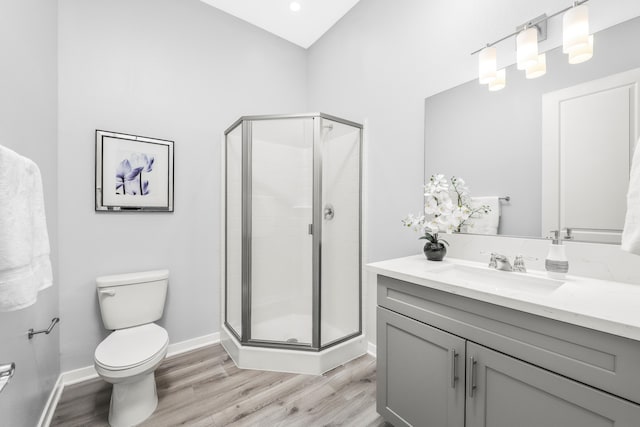 bathroom featuring hardwood / wood-style floors, vanity, toilet, and a shower with door